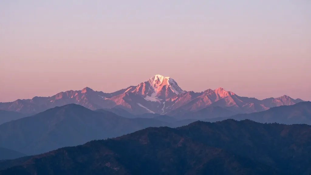 Distant dawn panorama of pink-tinged mountain peaks at sunrise