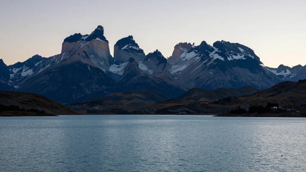 Distant alpine blue lake with the Paine Massif silhouette at sunset