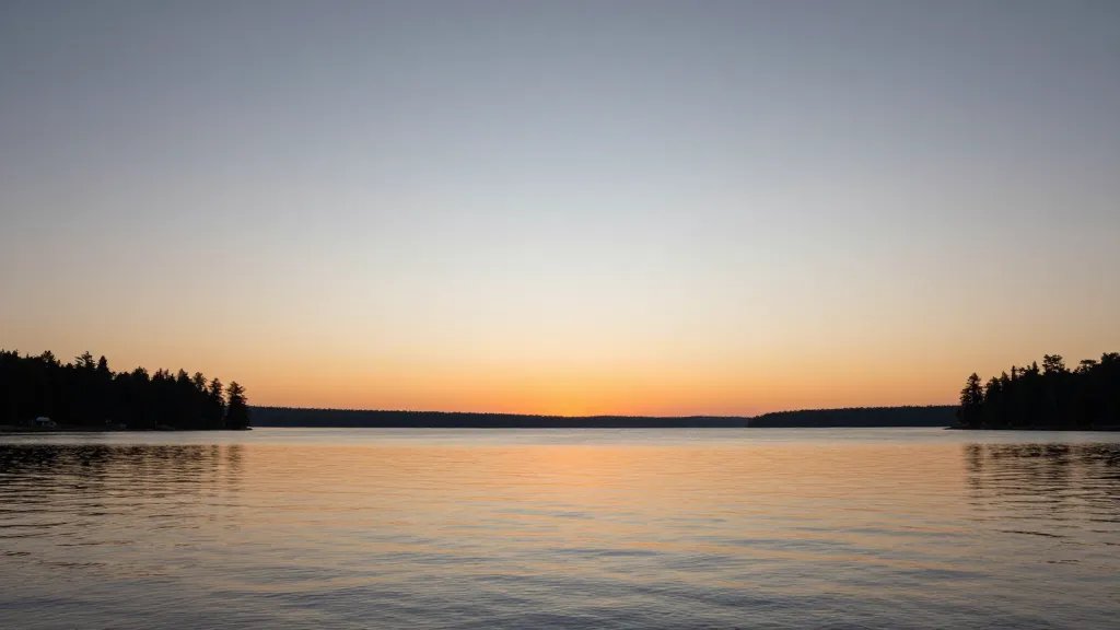 Wide-angle sunset over Boundary Lake Preserve with calm shoreline and distant pines