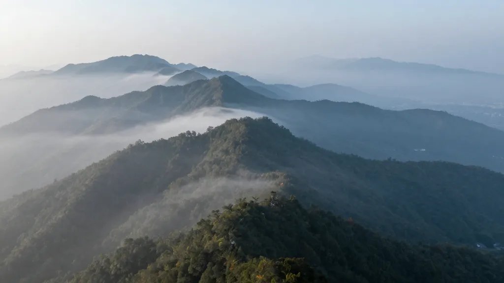 Expansive high-altitude ridge framed by cool morning mist and distant peaks