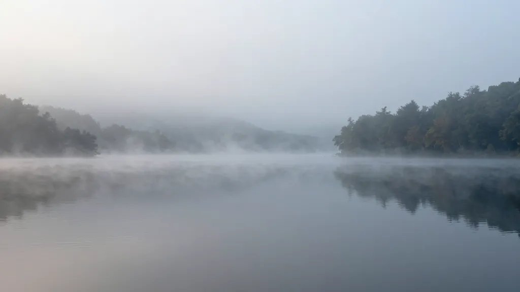Distant view of Misty Lake with glassy surface and morning fog