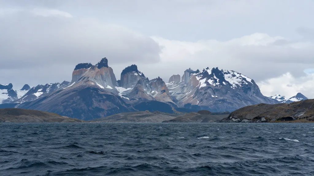 Distant panorama of Patagonian granite towers rising above wind-swept water