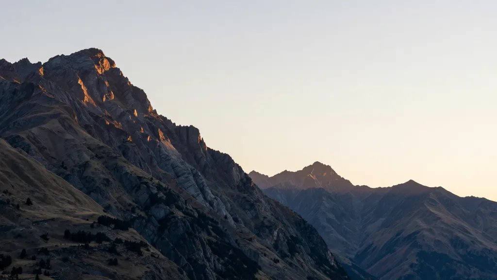 Far cliffside spine of The Remarkables against pale sunrise sky, Queenstown