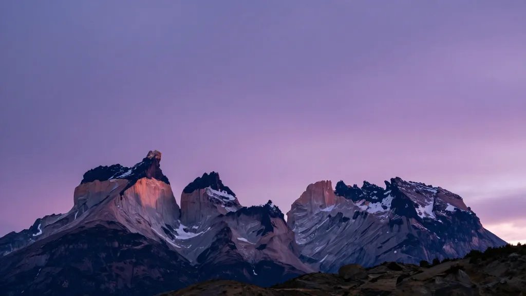 Wide-angle shot of Towers del Paine crenellated peaks against violet sunrise skies