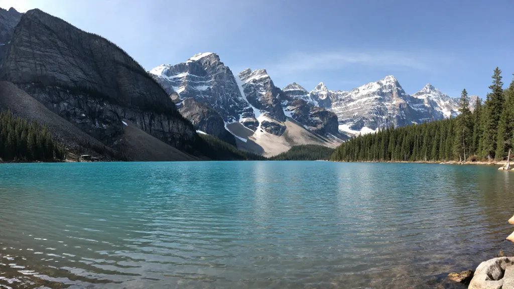 Wide-angle shot of crystal-clear Banff lake and pine-dotted peaks far away