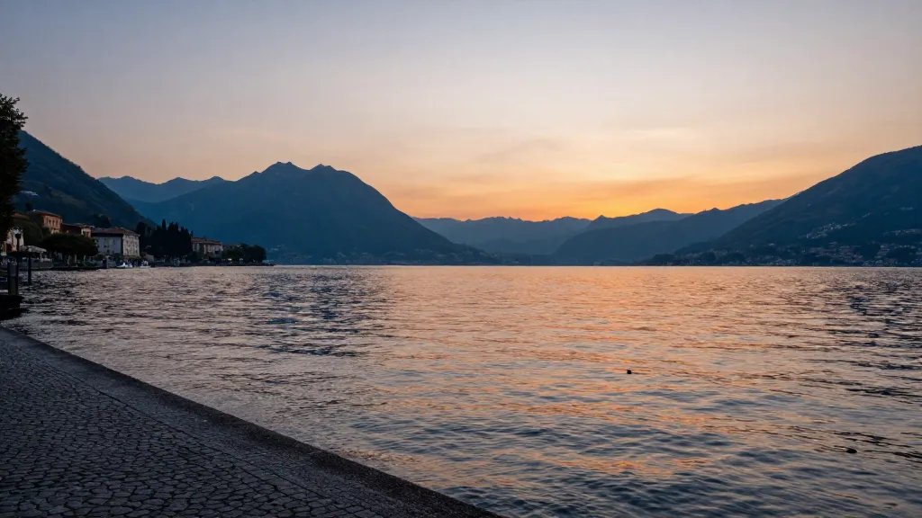 Wide shot of Lake Como reflecting sunset hues over tranquil promenade
