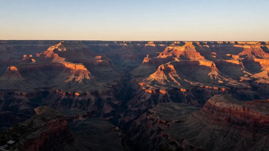 Wide-angle view of canyon walls glowing at sunrise, distant, minimal foreground