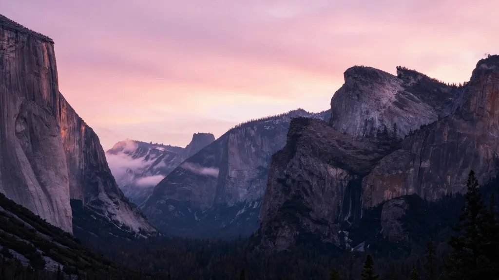 Distant pink-hued Half Dome silhouette with early light over Yosemite meadows