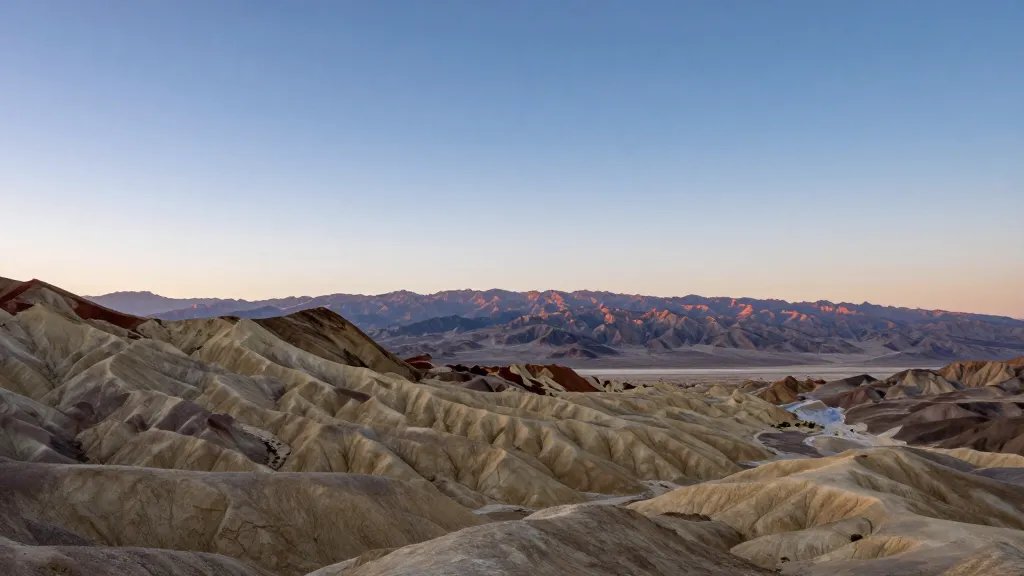 Wide-angle view of Death Valley badlands under expansive sky at sunrise