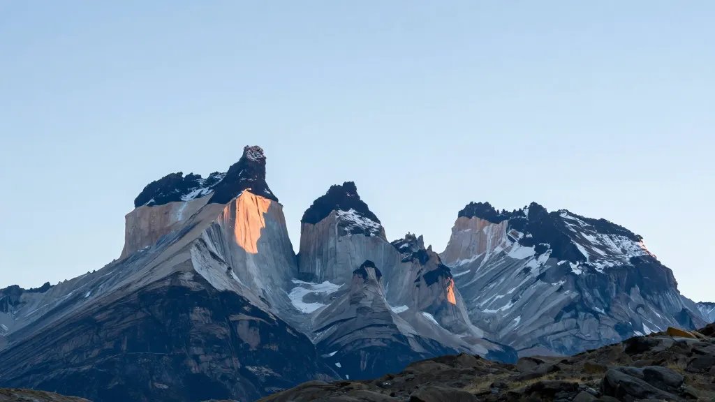 Distant view of Torres del Paine granite towers under pale blue sky