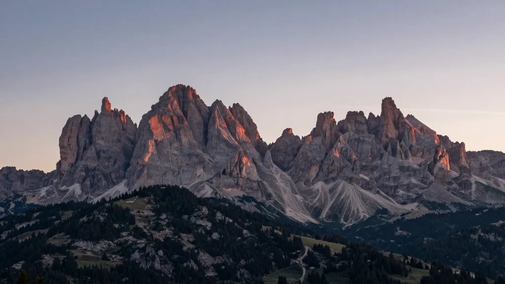 Distant view of Dolomites Valle di Funes spires at sunset