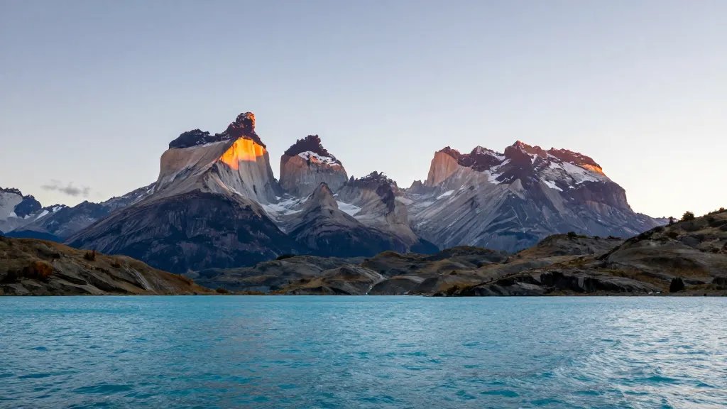 Distant sunrise view of Torres del Paine granite towers over turquoise Lake Pehoé