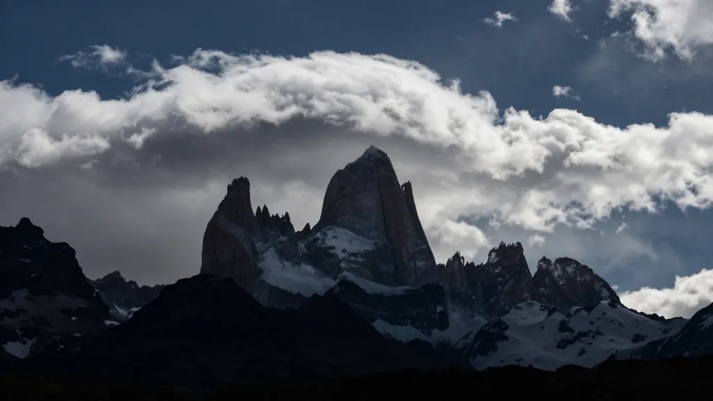 Isolated mountain silhouette with dramatic Patagonia clouds over base of towers